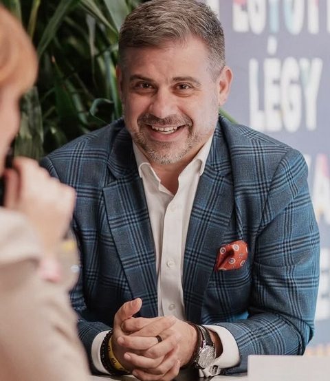 Gáspár András beszélgetés közben, asztal mellett, zakóban